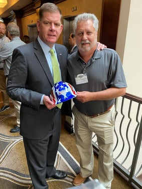 Anthony H. Nicholson, IAHFIAW International Representative to the TVTLC, presents U.S. Secretary of Labor Marty Walsh with a patriotic colored hard hat with the Insulators Union logo.